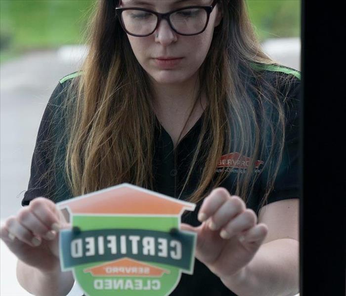 a SERVPRO employee placing a CSC sticker on building glass